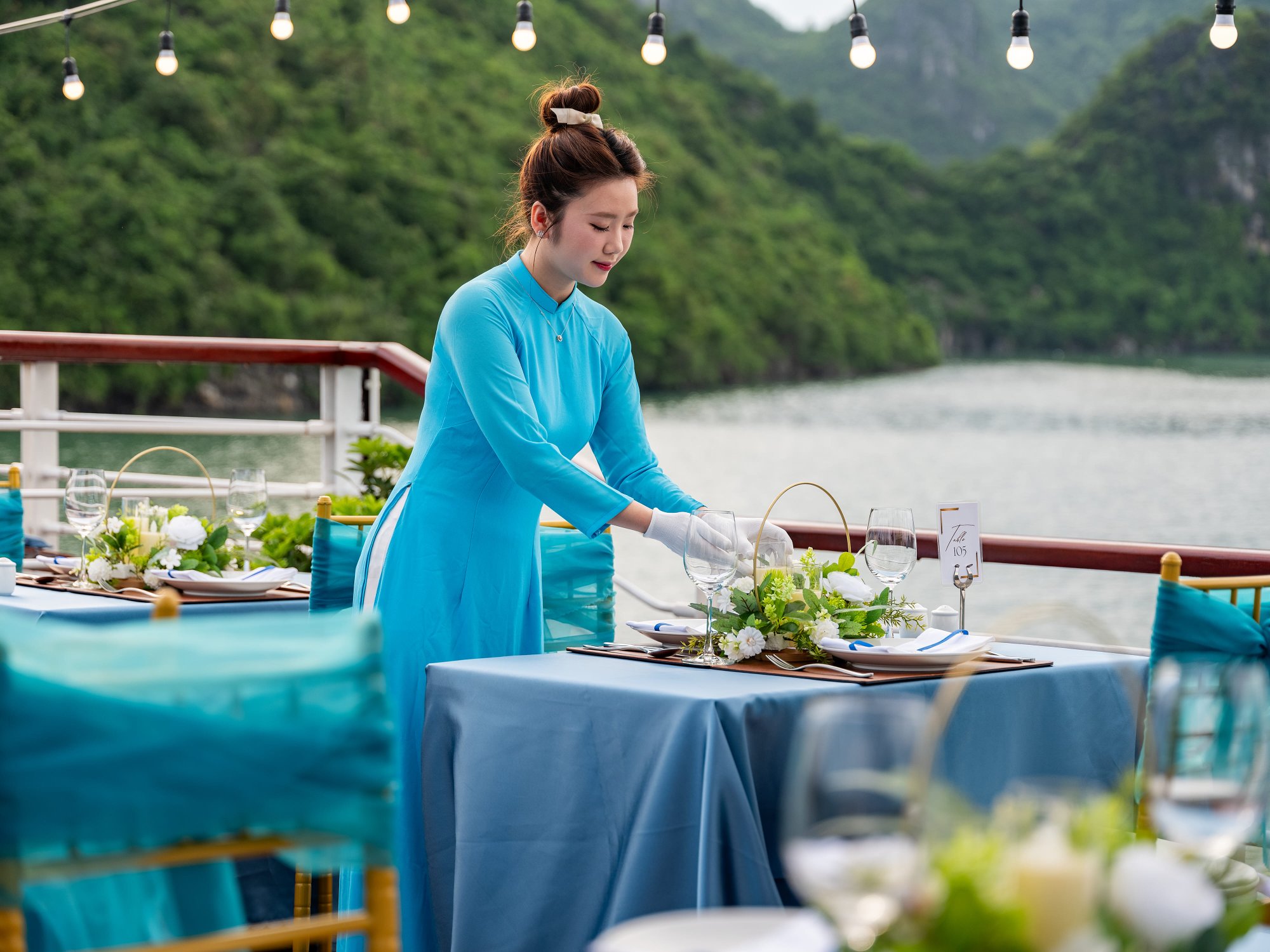 Staff in ao dai setting up a deck dining table