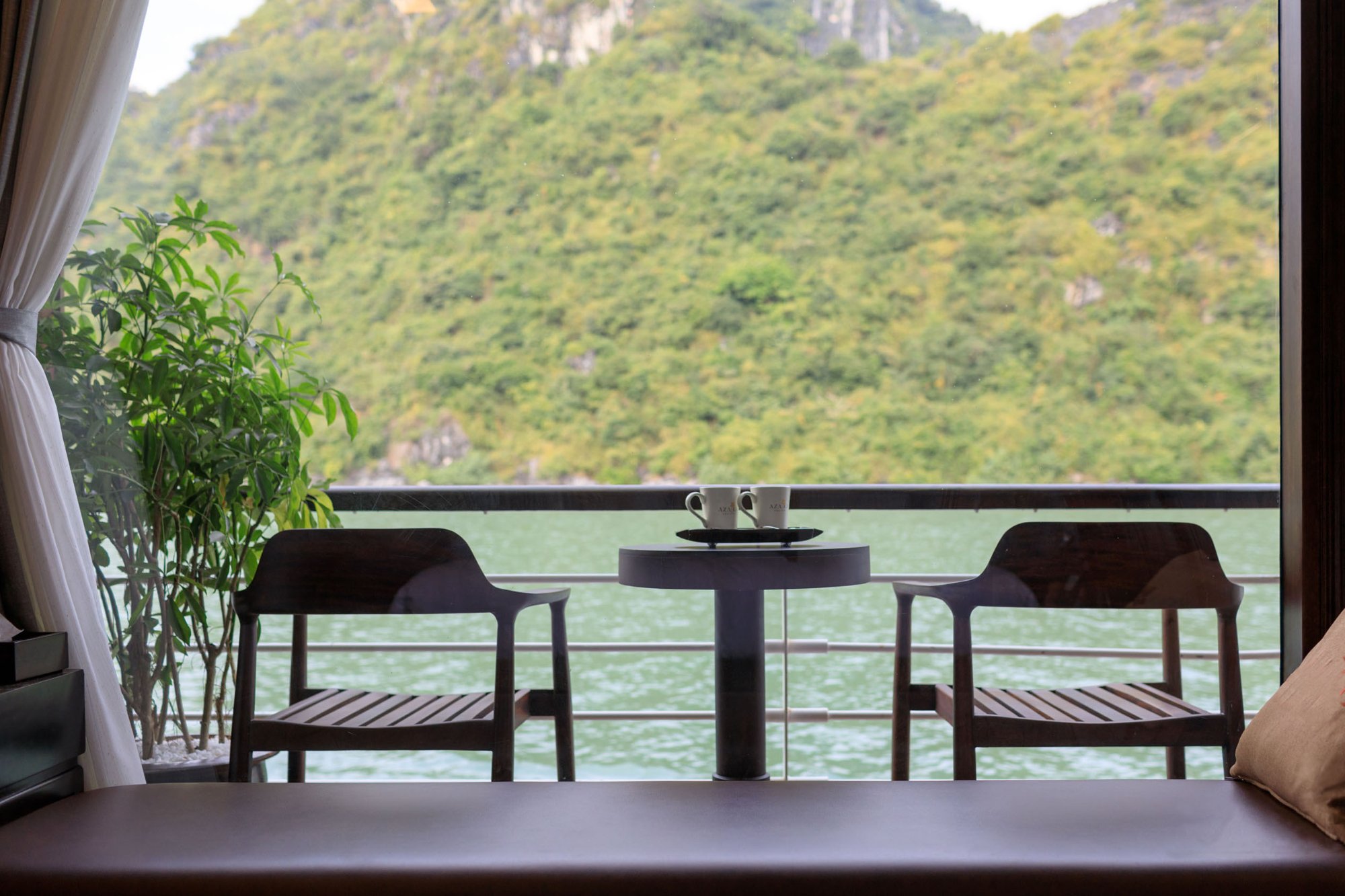Tea table on the balcony of a cruise cabin overlooking limestone karsts